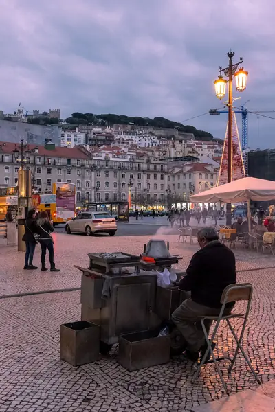 Vendedor de castanhas assadas ao fim do dia na Praça da Figueira, em Lisboa, com o fumo do assador