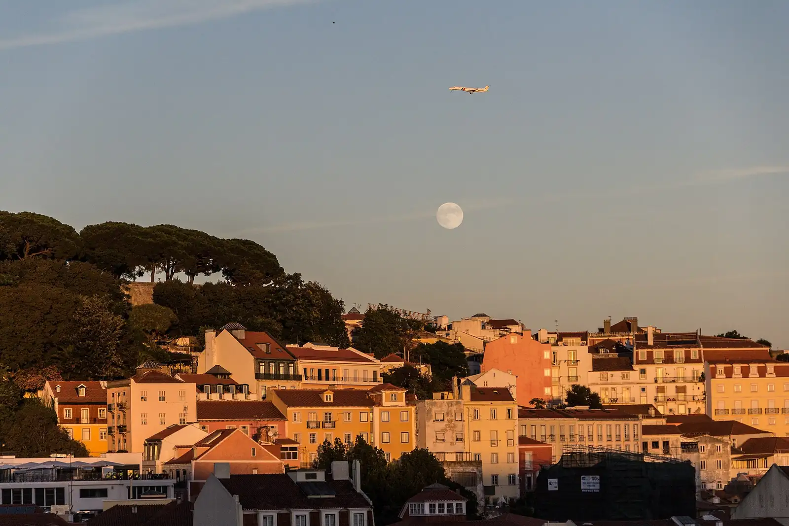 Lua cheia a nascer sobre os prédios de Lisboa ao fim do dia