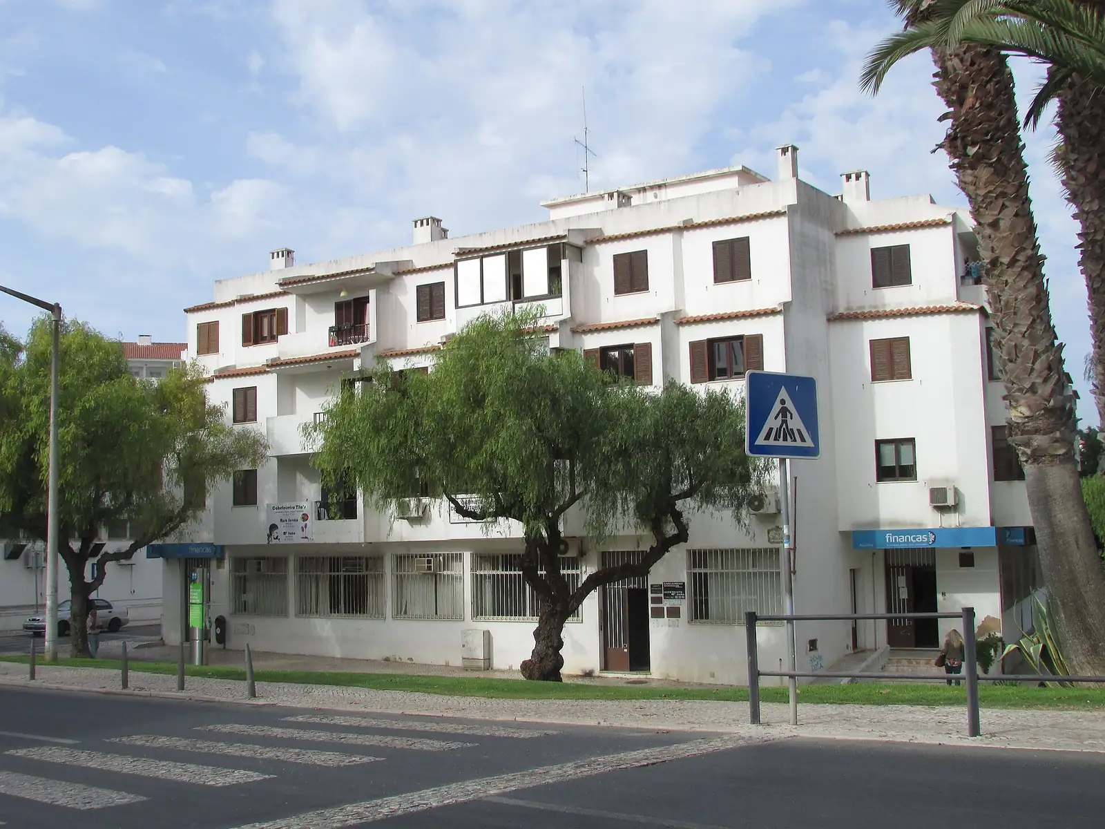 Edifício branco do Serviço de Finanças de Albufeira, com palmeiras e céu azul