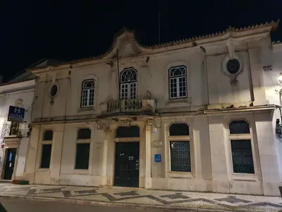 Fachada do Serviço de Finanças de Estremoz, um edifício antigo com janelas trabalhadas, ao anoitecer